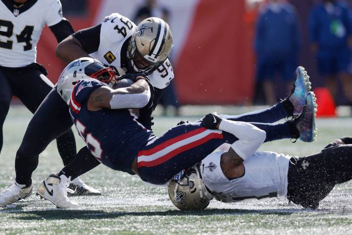 New England Patriots running back Ezekiel Elliott, center, is brought down by New Orleans Saint ...