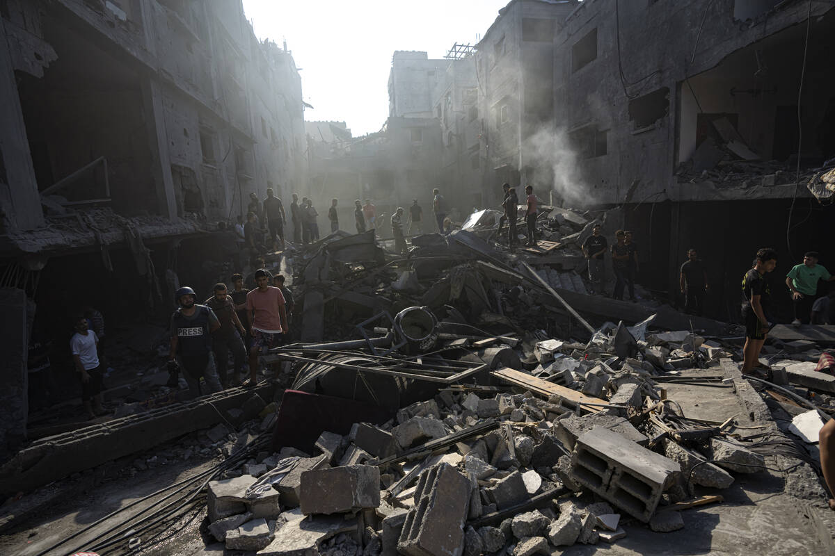 Palestinians search for bodies and survivors in the rubble of a residential building leveled in ...