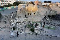 People stand outside a mosque destroyed in an Israeli air strike in Khan Younis, Gaza Strip, Su ...