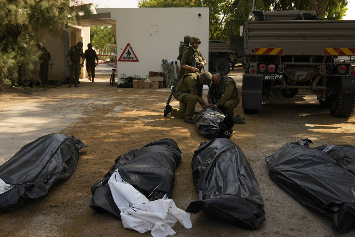 Israeli soldiers stand next to the bodies of Israelis killed by Hamas militants in kibbutz Kfar ...