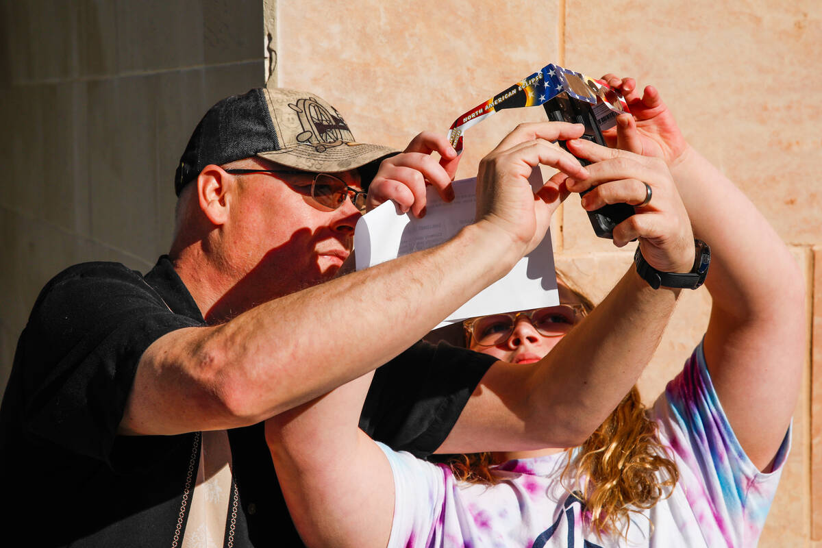 Bruce and Grace Heltzer take a photo of the annular solar eclipse through special viewing glass ...