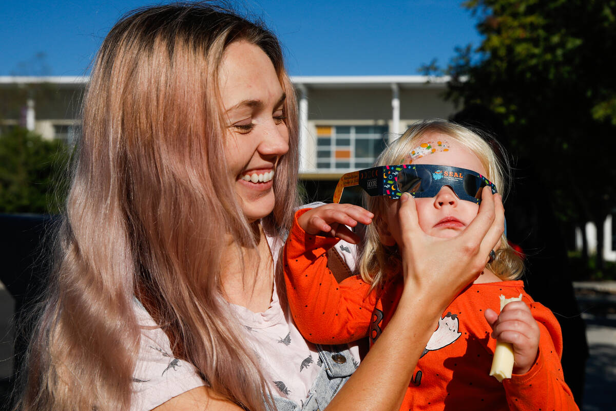 Des Leavitte puts solar eclipse glasses on her son, Zen Leavitte, as they view the annular sola ...