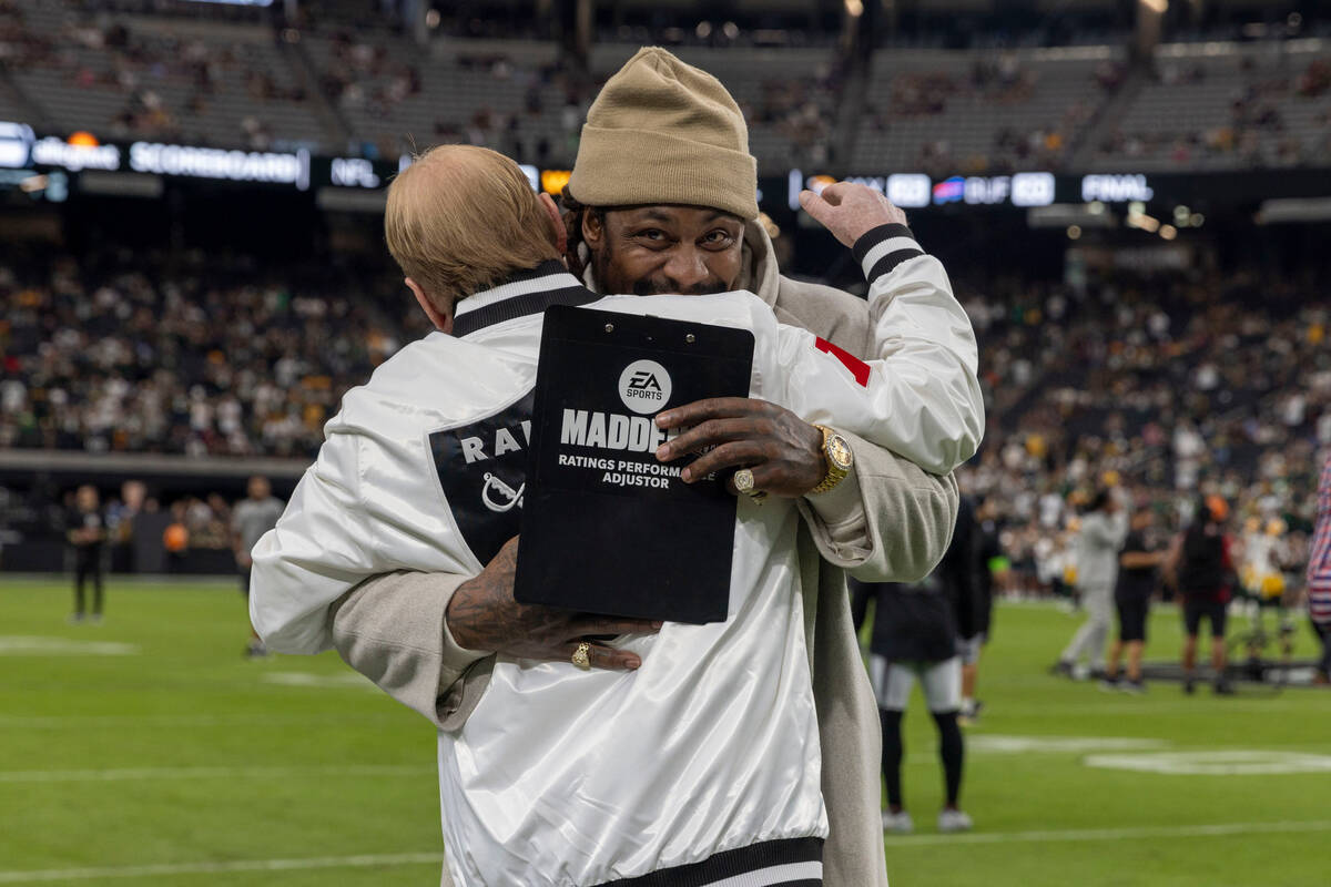 Former Raiders running back Marshawn Lynch hugs owner Mark Davis before an NFL game between the ...