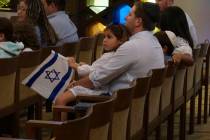 A family with Israel flags attends Shabbat services at Temple Beth Sholom in Miami Beach, Fla., ...