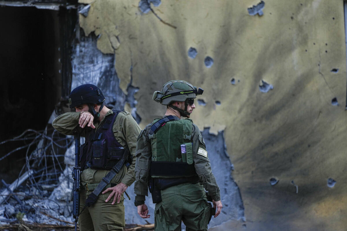 Israeli soldiers walk past destroyed houses in Kibbutz Be'eri, Israel, on Saturday, Oct. 14, 20 ...