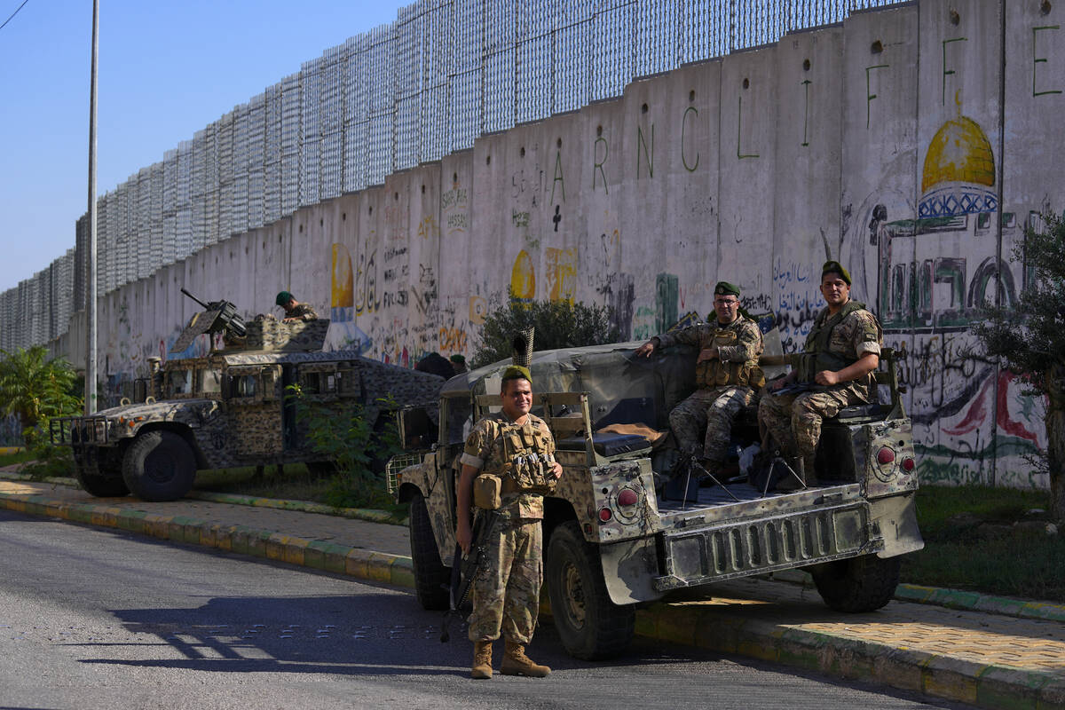 Lebanese army soldiers sit on their armored vehicles next to the wall that separates Lebanon fr ...