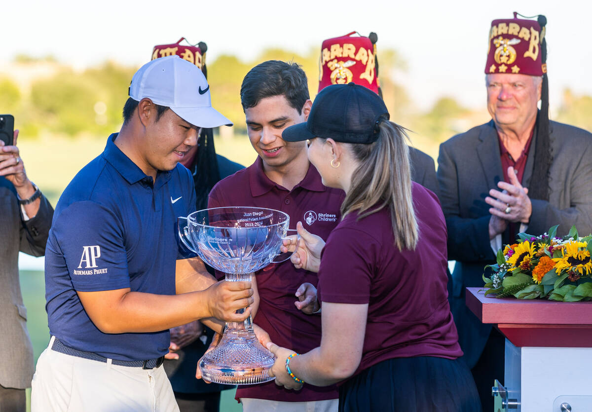 Tom Kim is handed the winning trophy by international patient ambassadors Juan Diego and Gianna ...