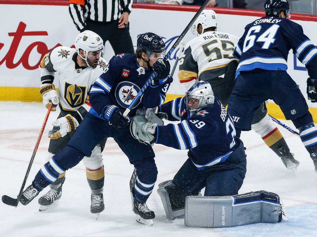 Winnipeg Jets goaltender Laurent Brossoit (39) saves the shot as Morgan Barron (36) defends aga ...