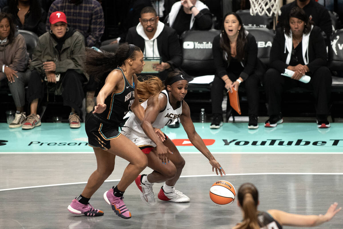 Las Vegas Aces guard Jackie Young (0) drives toward the hoop around New York Liberty forward Be ...