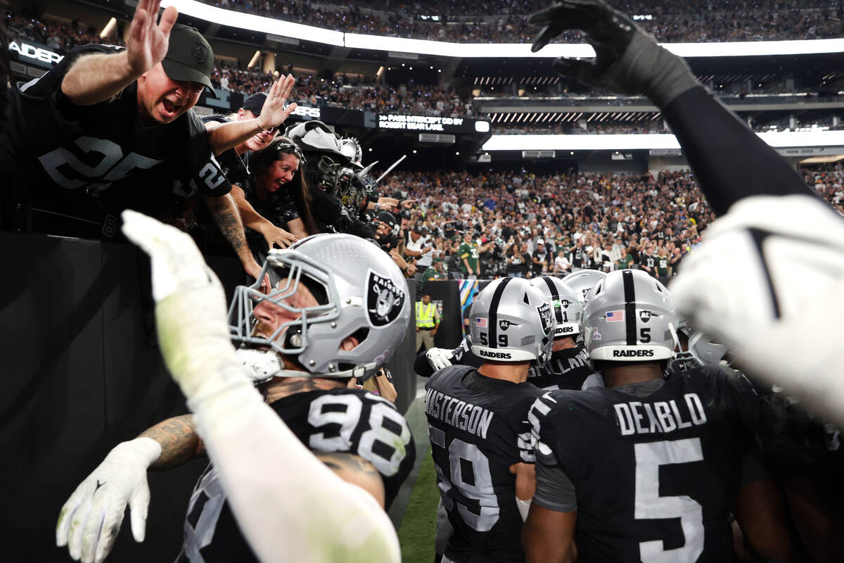 Raiders defensive end Maxx Crosby (98) celebrates an interception with fans against the Green B ...