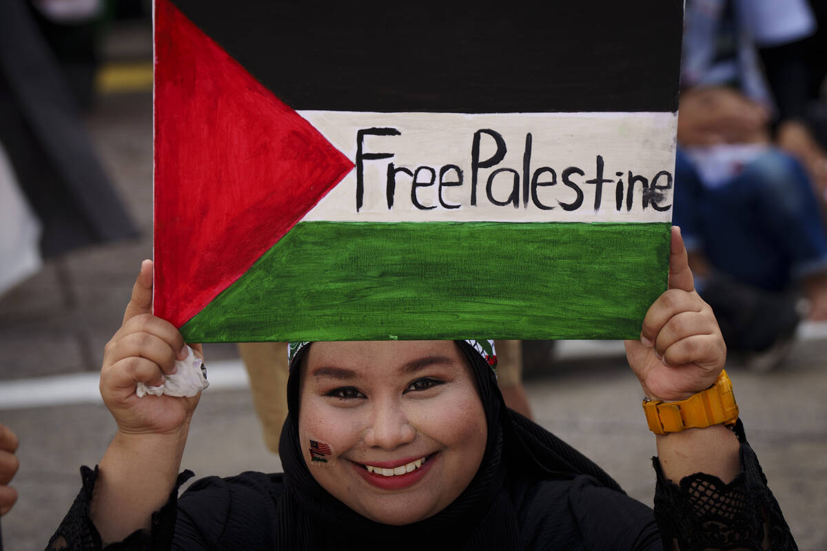 A Malaysian Muslim holds a poster representing the Palestinian flag during a rally to show her ...