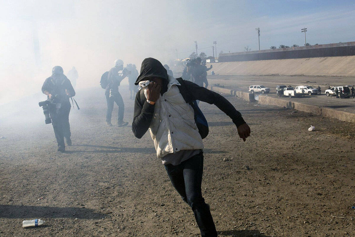 A migrant runs from tear gas launched by U.S. agents. (AP Photo/Rodrigo Abd)