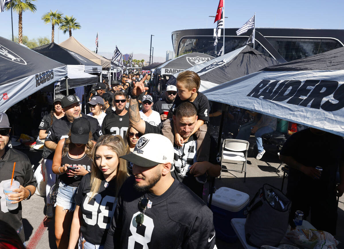 Raiders fans tailgate outside Allegiant Stadium before the start of an NFL football game betwee ...