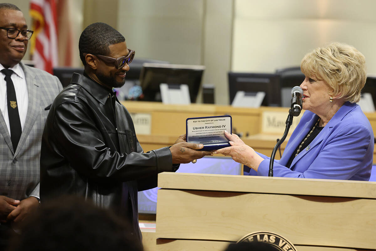Usher, center, receives a key to the City of Las Vegas from Mayor Carolyn Goodman as Councilman ...