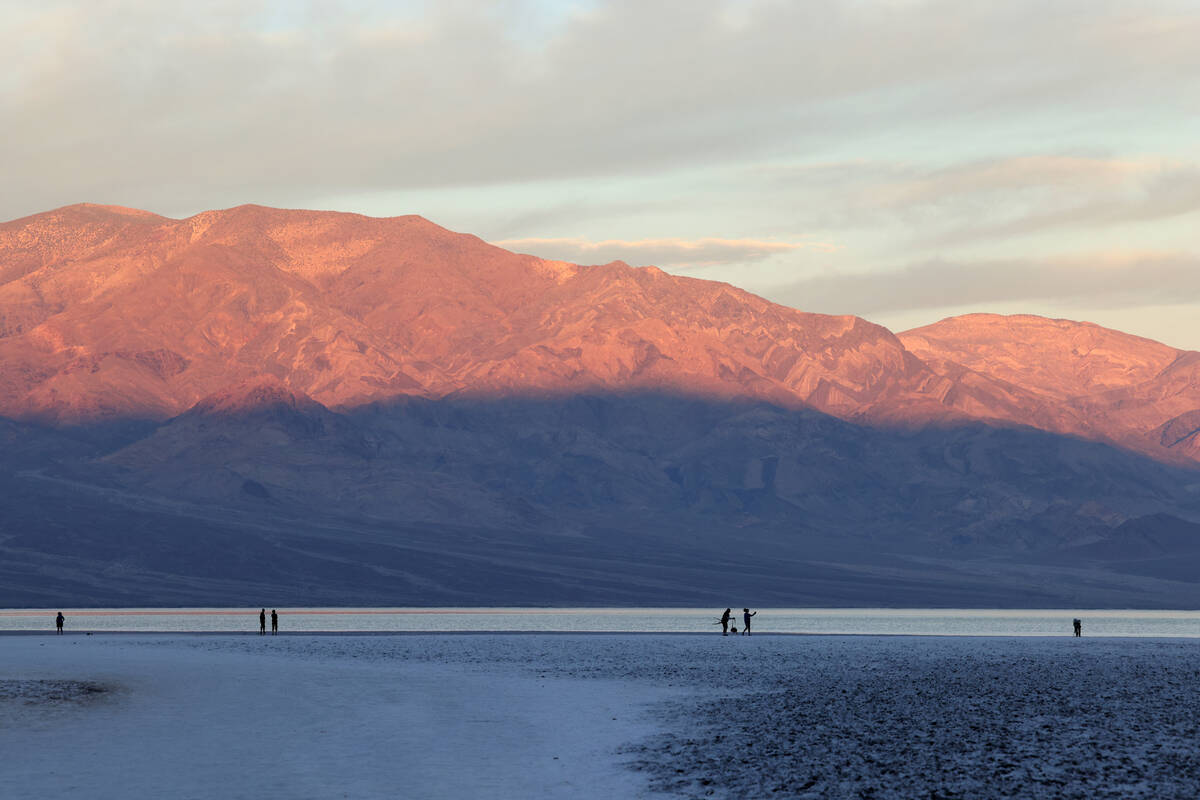 Visitors check out a rare lake in Badwater Basin in the recently reopened Death Valley National ...