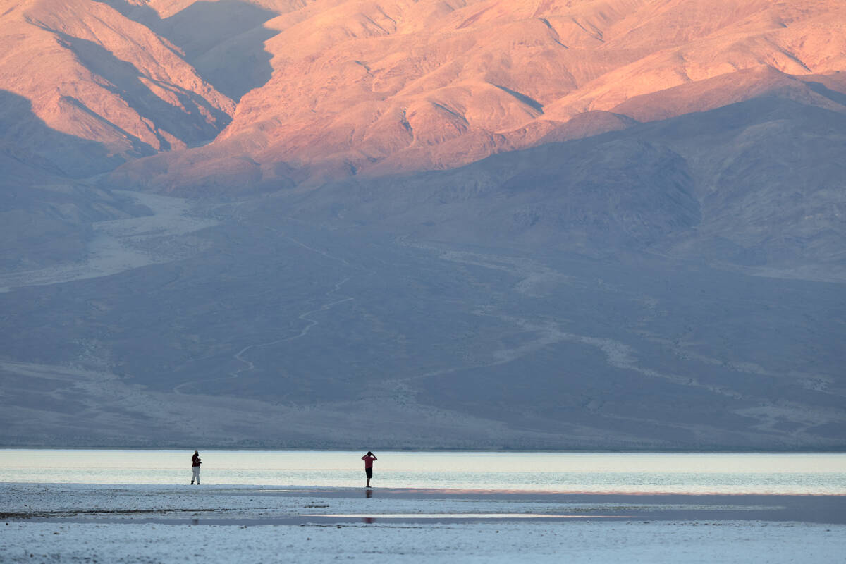 Visitors check out a rare lake in Badwater Basin in the recently reopened Death Valley National ...