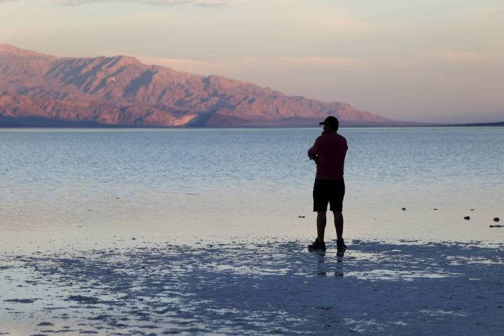 A visitor checks out a rare lake in Badwater Basin in the recently reopened Death Valley Nation ...