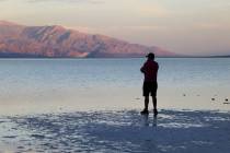 A visitor checks out a rare lake in Badwater Basin in the recently reopened Death Valley Nation ...