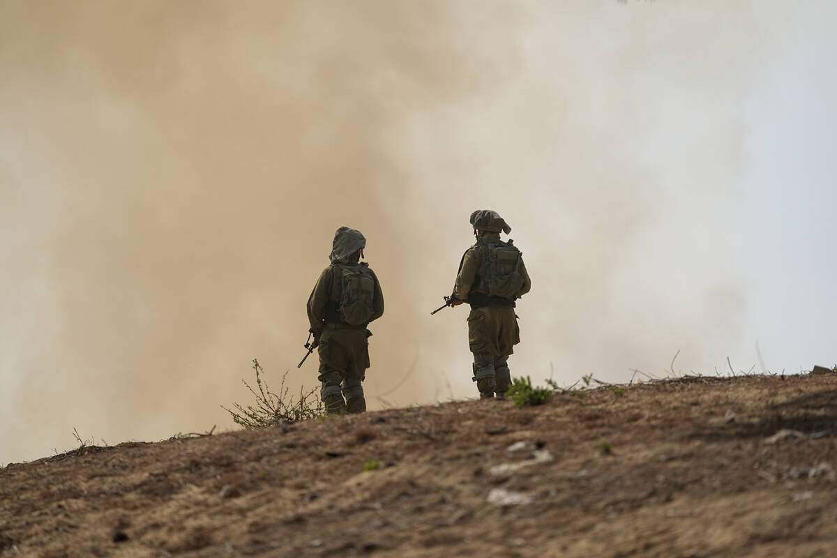 Israeli soldiers stand next to a burning field near the border with the Gaza Strip, in southern ...