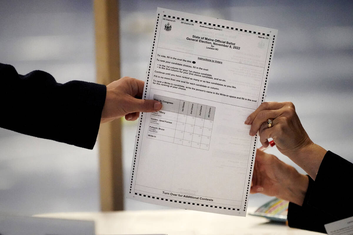 A ballot showing the choices for Maine's 2nd Congressional District is handed to a voter, Tuesd ...
