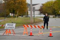A police officer stands at a road closure near a bowling alley, seen in background, Thursday, O ...