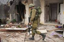 An Israeli soldier walks past a house damaged during the Hamas attack in Kibbutz Kfar Azza, Isr ...