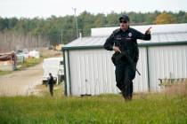 A police officer gives an order to the public during a manhunt at a farm for the suspect in thi ...