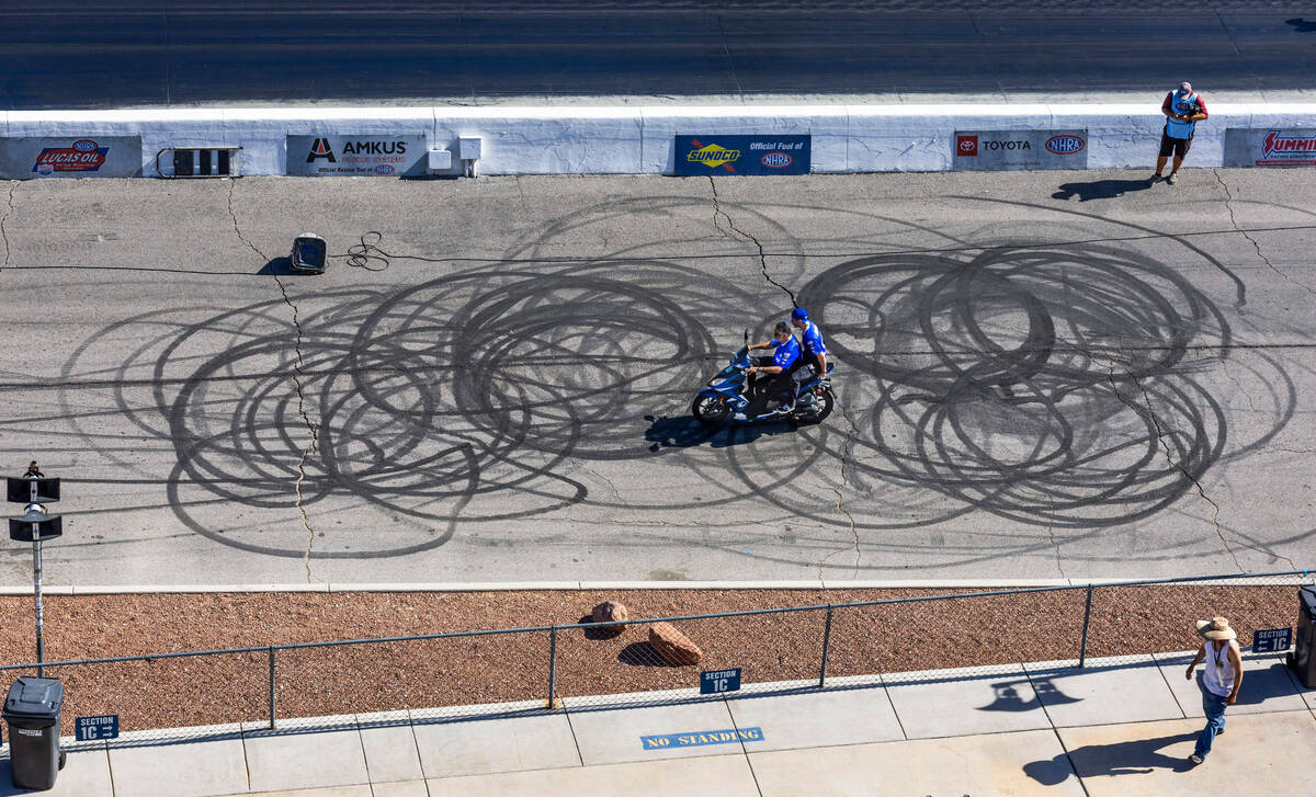 Support staff make their way down the side of the track during a qualifying session in the NHRA ...