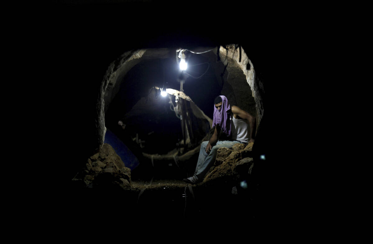 FILE - A Palestinian worker rests inside a smuggling tunnel in Rafah, on the border between Egy ...