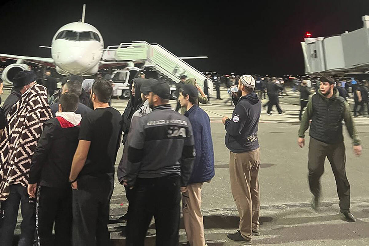 People in the crowd walk shouting antisemitic slogans at an airfield of the airport in Makhachk ...