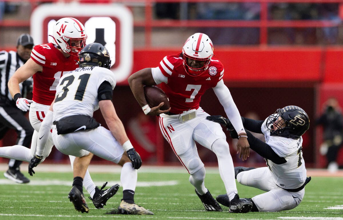 Nebraska quarterback Jeff Sims, center, carries the ball against Purdue's Dillon Thieneman, sec ...