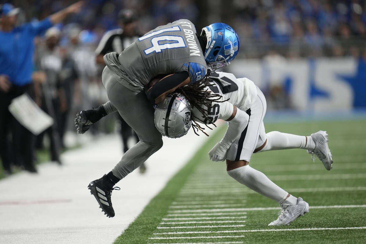Detroit Lions wide receiver Amon-Ra St. Brown (14) is pushed out of bounds by Las Vegas Raiders ...