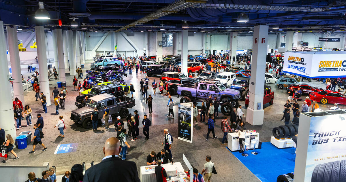 Attendees move about some of the custom vehicles on display during the first day of SEMA at the ...