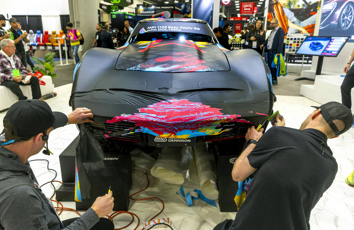A crew from Avery Dennison applies a wrap to a Corvette during the first day of SEMA at the Las ...