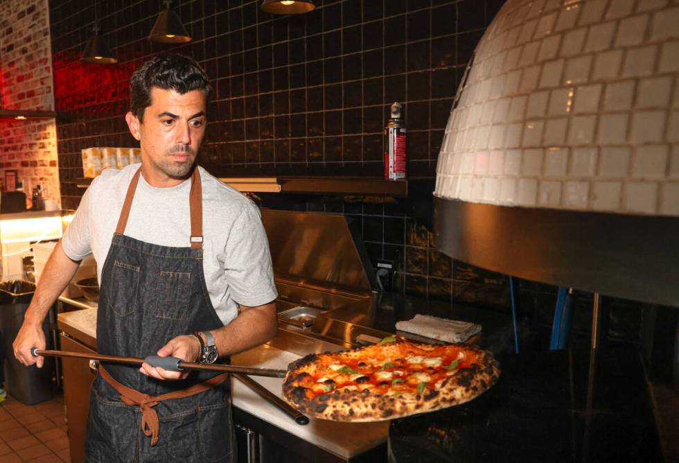 World champion pizza maker Michael Vakneen pulls out a pizza from the oven at his new restauran ...