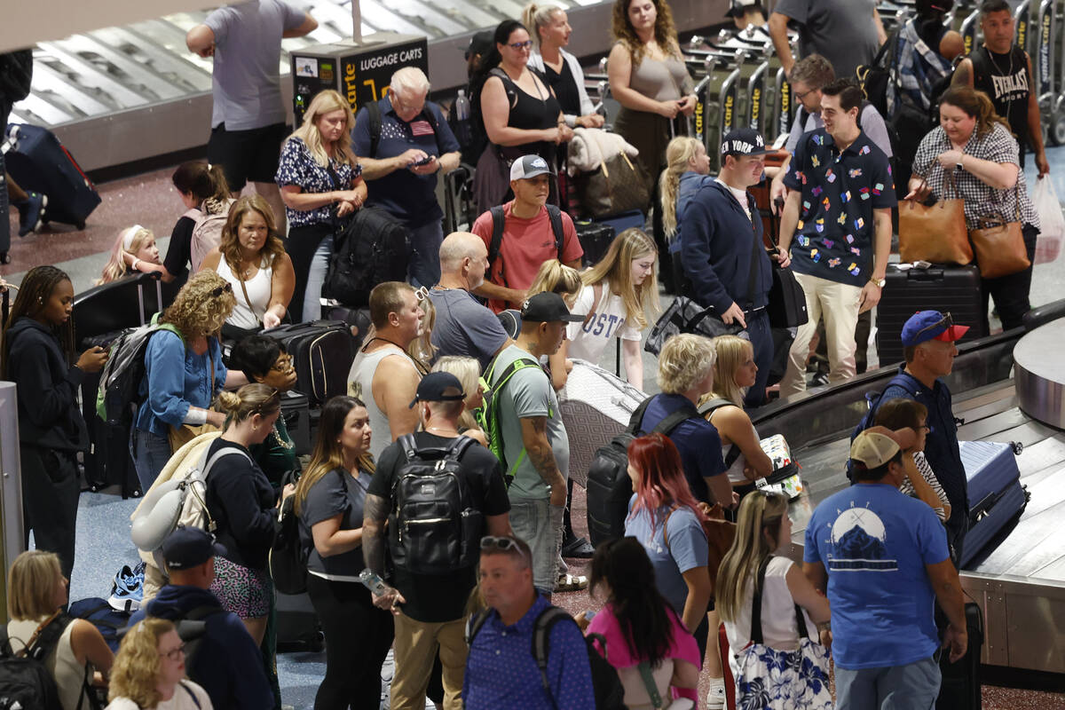 People wait for their luggage at a baggage carousel at Harry Reid International Airport, Friday ...