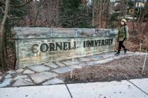 FILE - A woman walks by a Cornell University sign on the Ivy League school's campus in Ithaca, ...