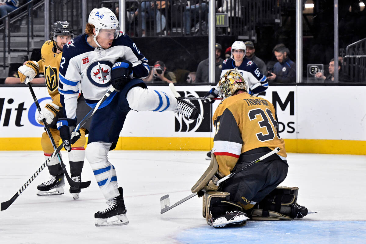 Vegas Golden Knights goaltender Logan Thompson (36) looks down at the puck, next to Winnipeg Je ...