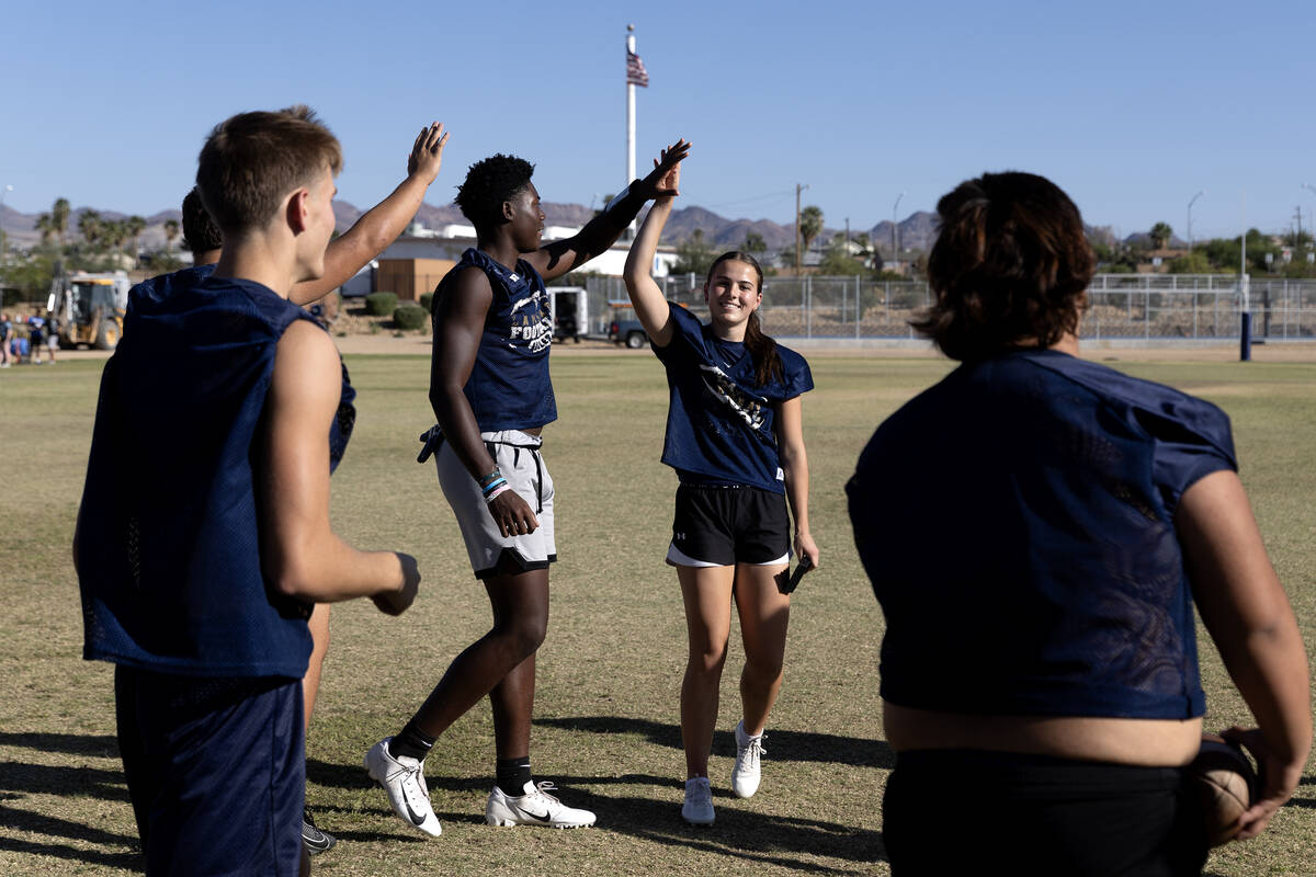 Kicker Gracie Rhodes, right, slaps hands with teammate Jaylen Hardy during football practice at ...