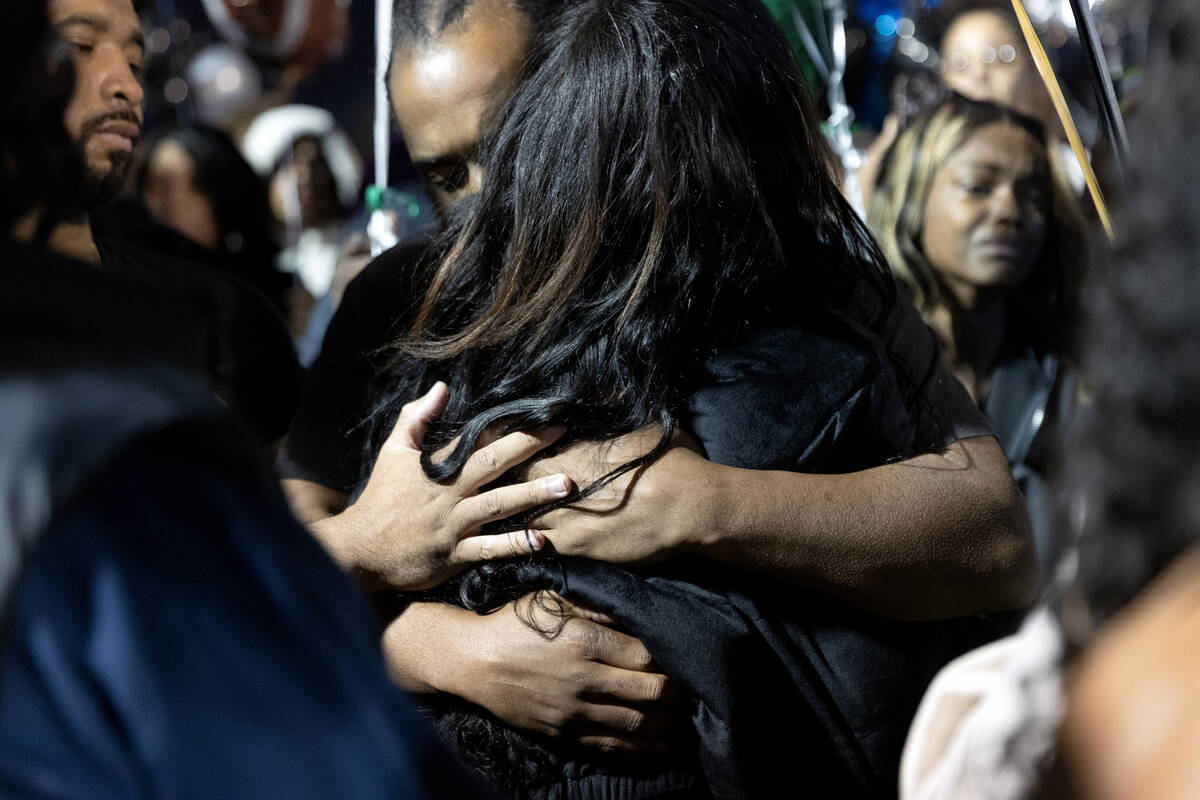 Maureisha Johnson is embraced during a vigil for her son, Desert Pines High School football pla ...