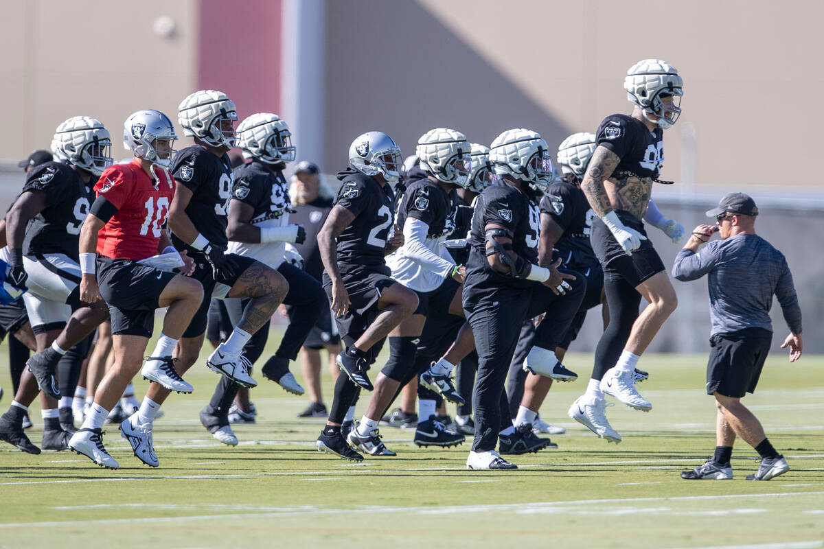 The Raiders, led by defensive end Maxx Crosby (98), warm up during practice at the Intermountai ...