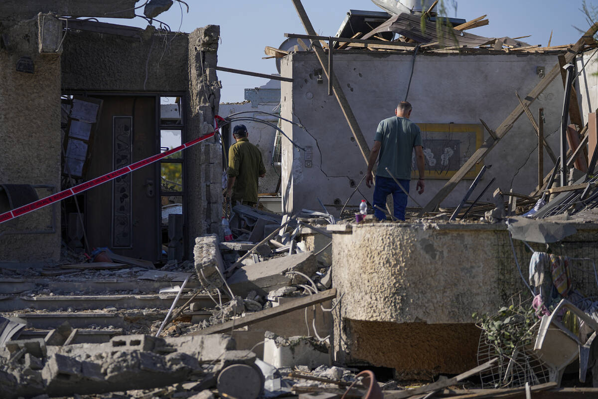 An Israeli reservist soldier, left, inspects the damage to his mother's house, a day after the ...