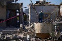An Israeli reservist soldier, left, inspects the damage to his mother's house, a day after the ...