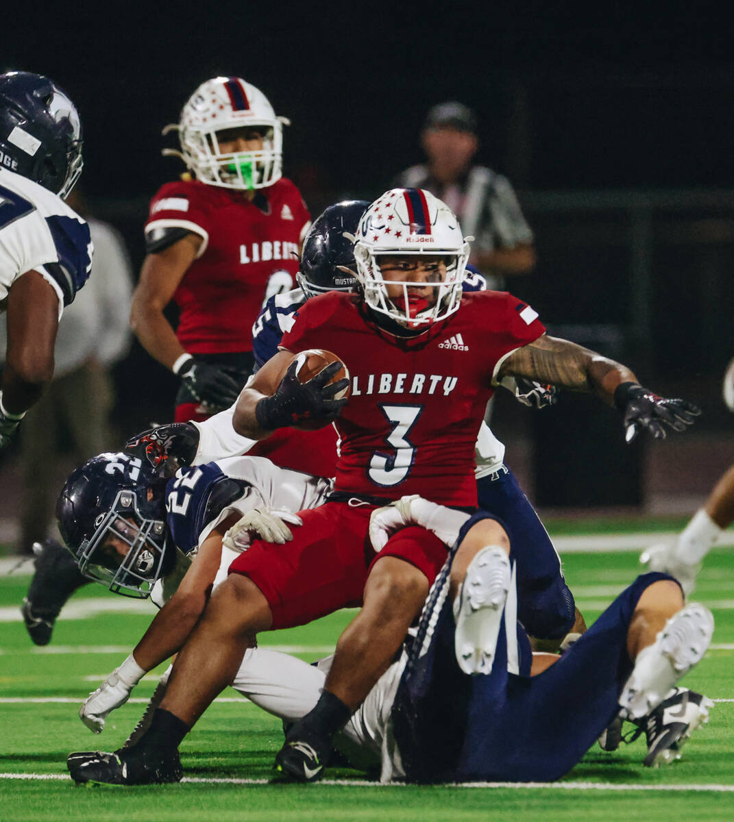 Liberty running back Isaiah Lauofo (3) tries to keep on his feet as he carries the ball past Sh ...