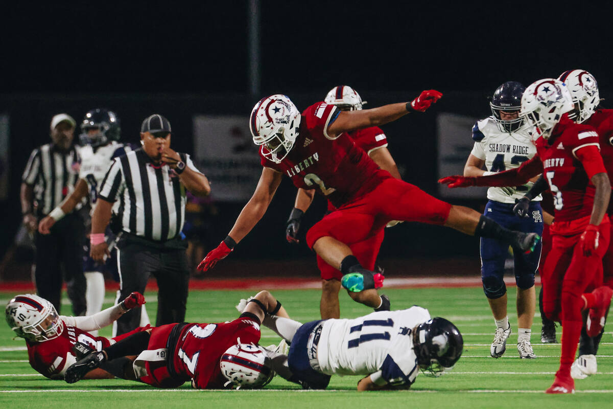 Liberty linebacker Andre Porter jumps over Shadow Ridge cornerback Joseph Darr during a game at ...