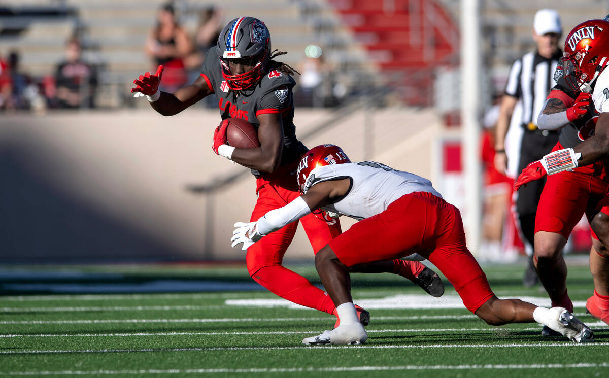 New Mexico's Caleb Medford looks for room to run against UNLV's Cameren Jenkins during an NCAA ...