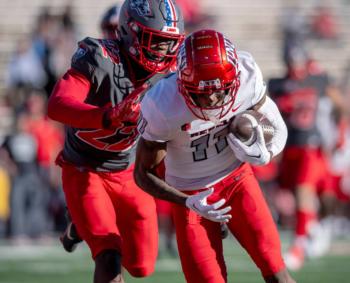 UNLV's Ricky White, right, runs a reception into the end zone in front of New Mexico's Christia ...
