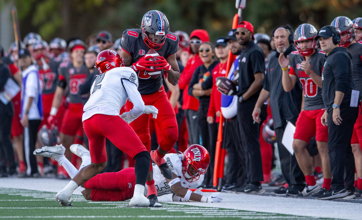 New Mexico's DJ Washington, center, makes a reception for a first down before being pushed out ...