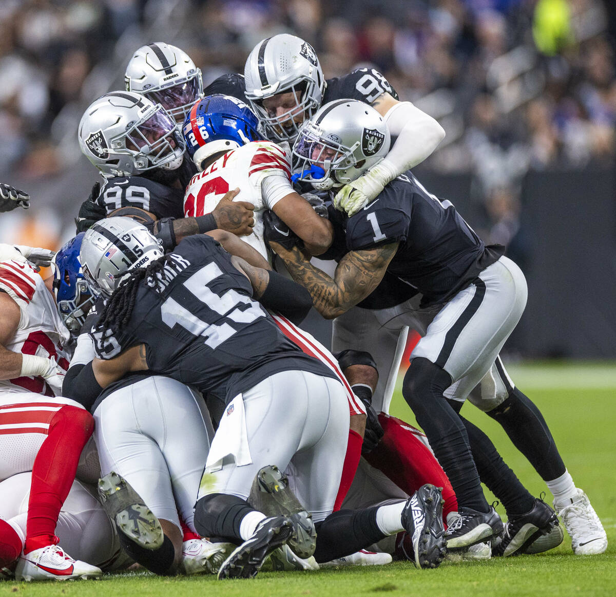 New York Giants running back Saquon Barkley (26) is swarmed on a tackle by the Raiders defense ...