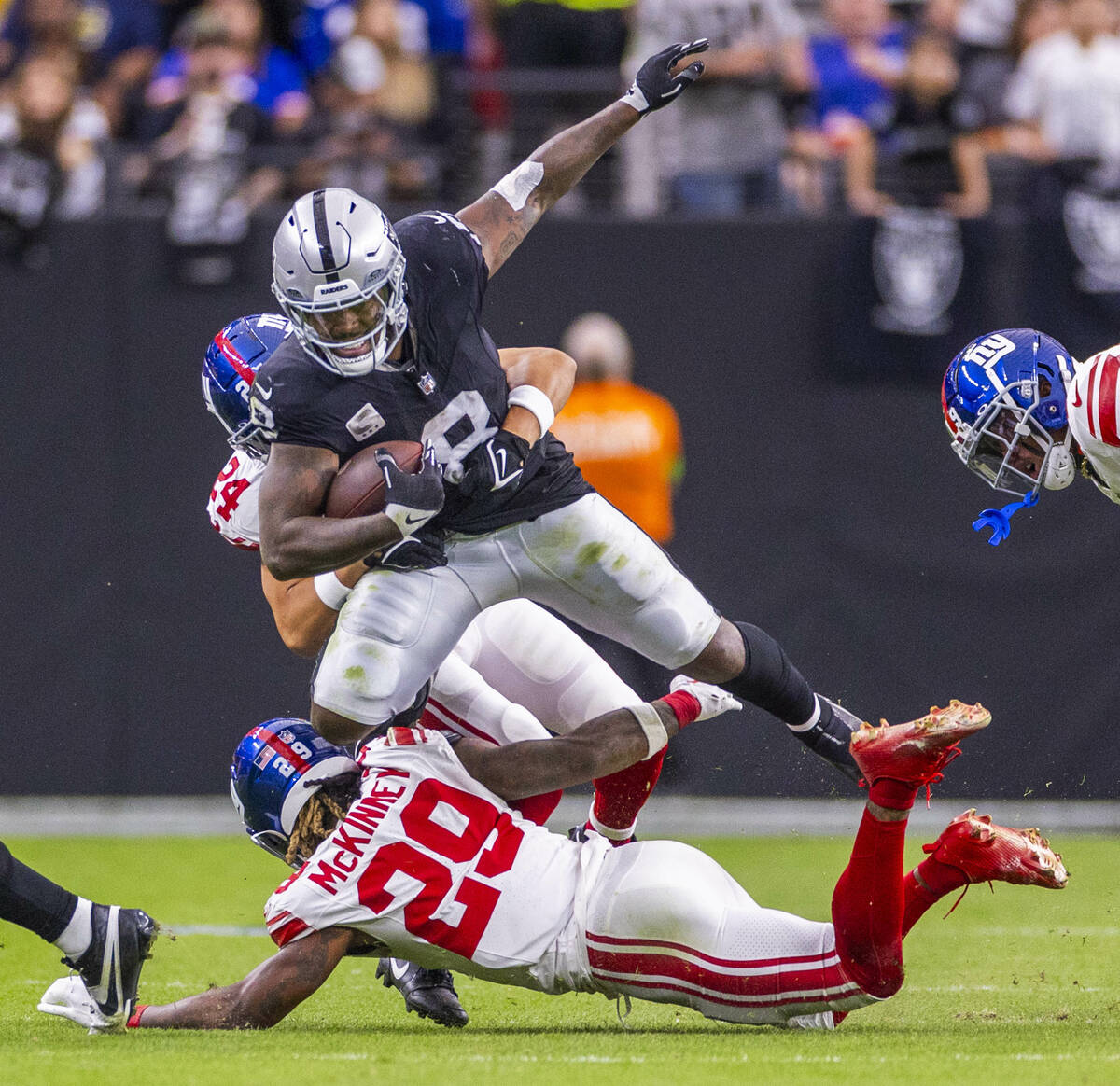 Raiders running back Josh Jacobs (8) is grabbed by New York Giants safety Dane Belton (24) whil ...
